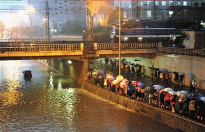 西三环莲花桥附近道路被雨水淹没，人们涉水通过该路段。